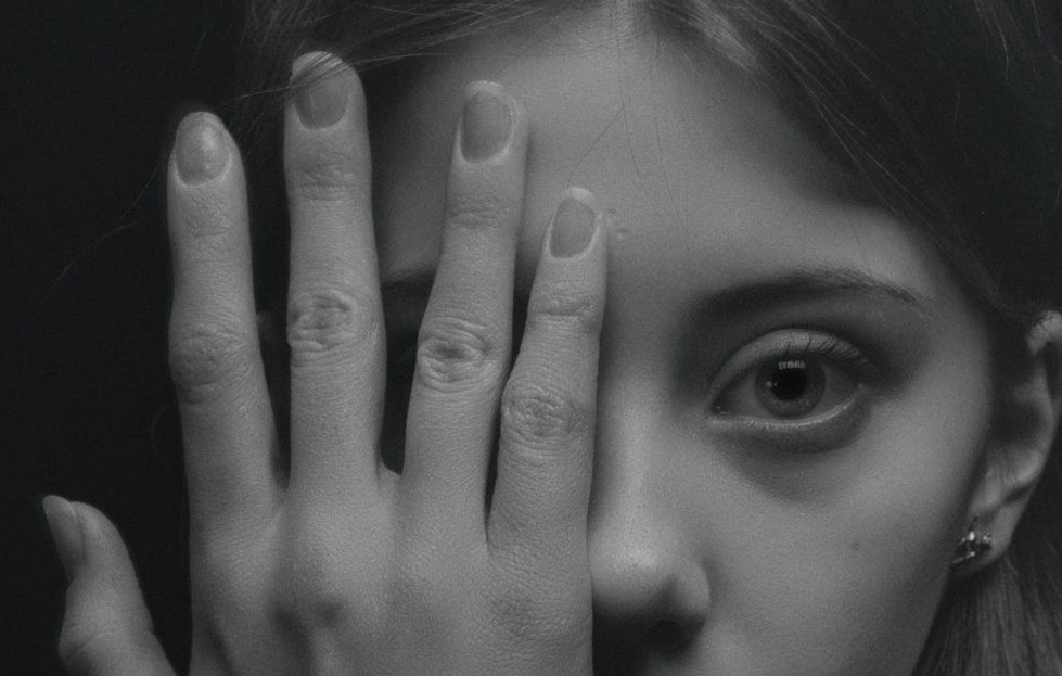 grayscale photo of woman covering her face by her hand