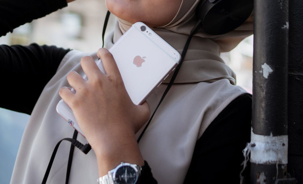 woman holding iphone and wearing headphones